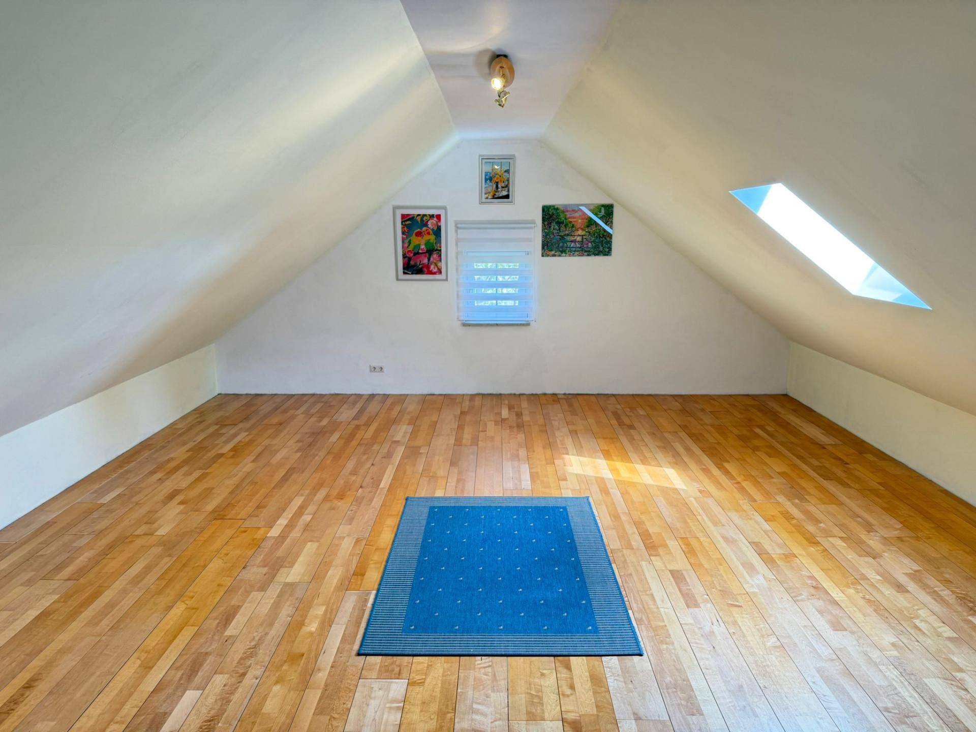 Geräumiger Dachbodenraum mit Holzfußboden und Dachfenster, ideal als Hobby- oder Abstellraum.