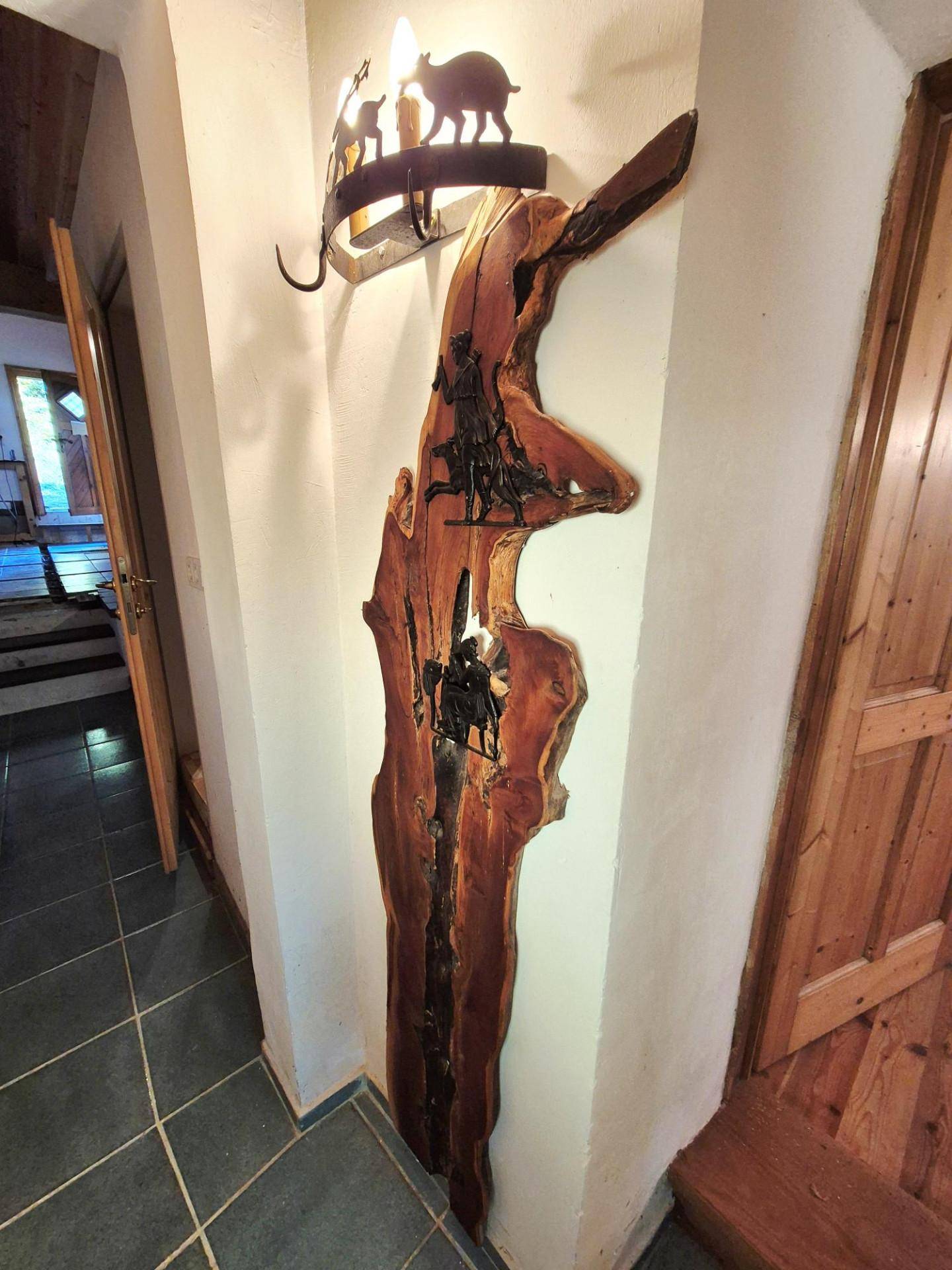 Flur mit dunklen Fliesen und einer rustikalen Wanddekoration aus Holz und Metall.