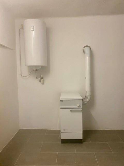 Hauswirtschaftsraum mit Warmwasserboiler und Heizungsanlage auf Fliesenboden.