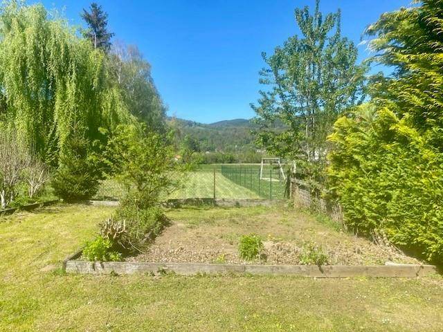 Großer Gartenbereich mit Rasenfläche, Beeten und Blick auf die umliegende Landschaft.