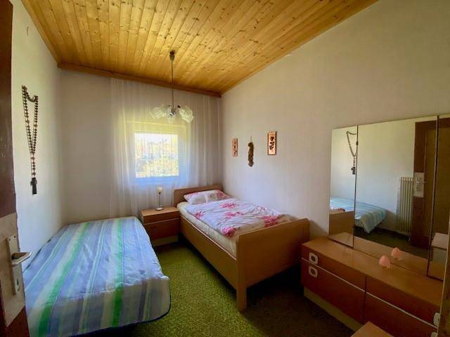 Schlafzimmer mit zwei Betten, Holzdecke und Blick ins Grüne.