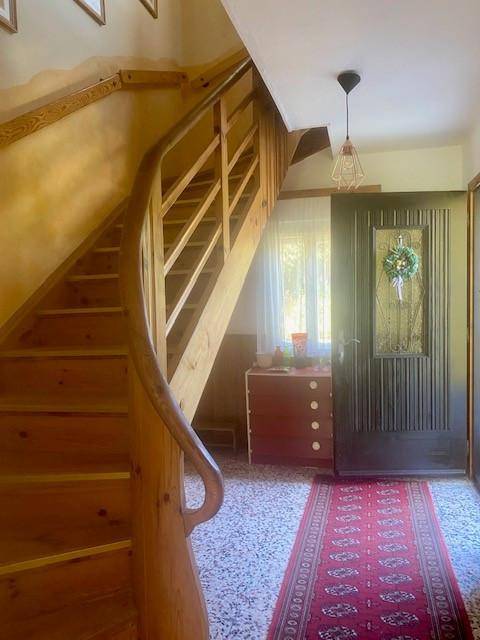 Heller Eingangsbereich mit Holztreppe und traditionellem Teppichläufer.