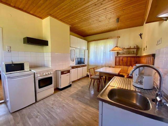 Gemütliche Küche mit Essbereich, Holzdecke und einfachen Einbaugeräten.