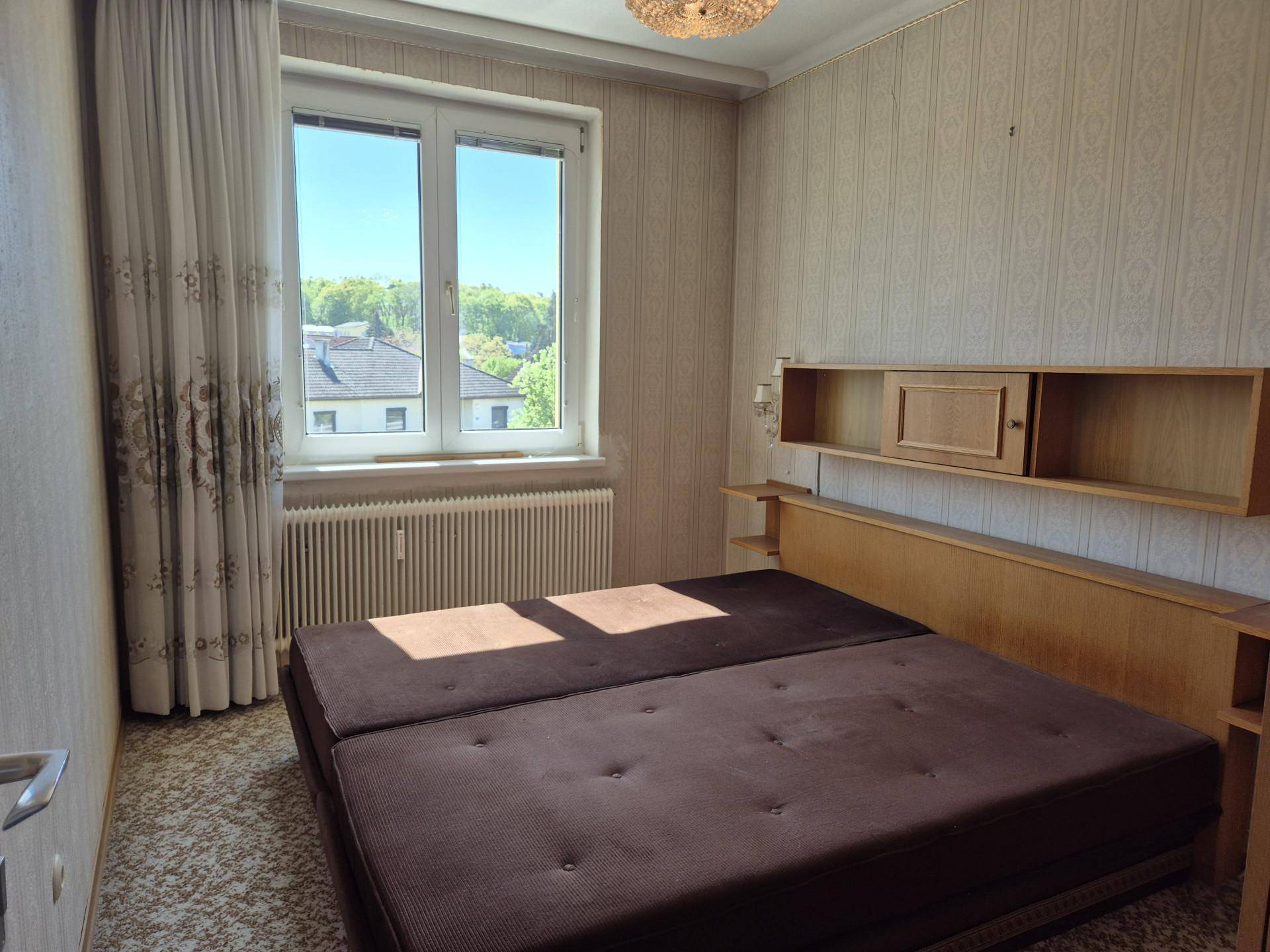 Helles Schlafzimmer mit Doppelbett, Teppichboden und Blick ins Grüne.