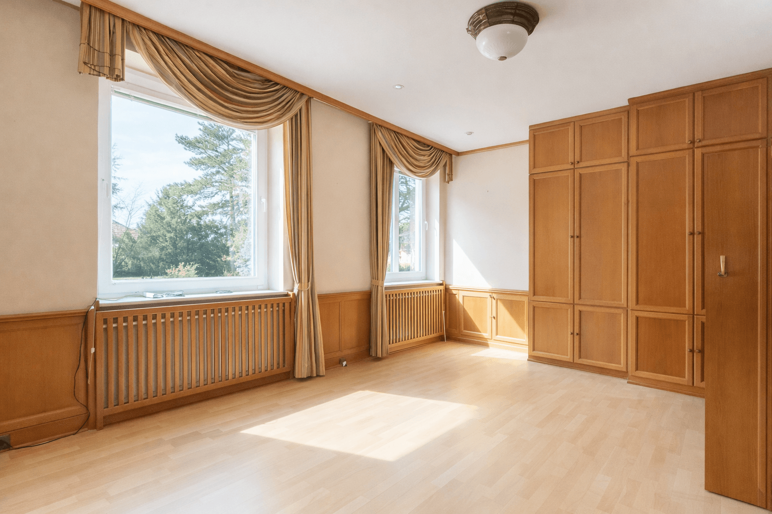Schlafzimmer mit Einbauschränken, Holzvertäfelung und Blick ins Grüne.