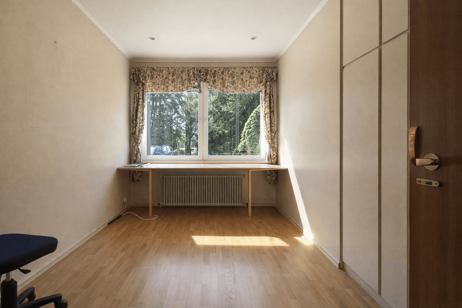 Helles Arbeitszimmer mit Laminatboden, Fenster zum Garten und integriertem Schreibtisch.