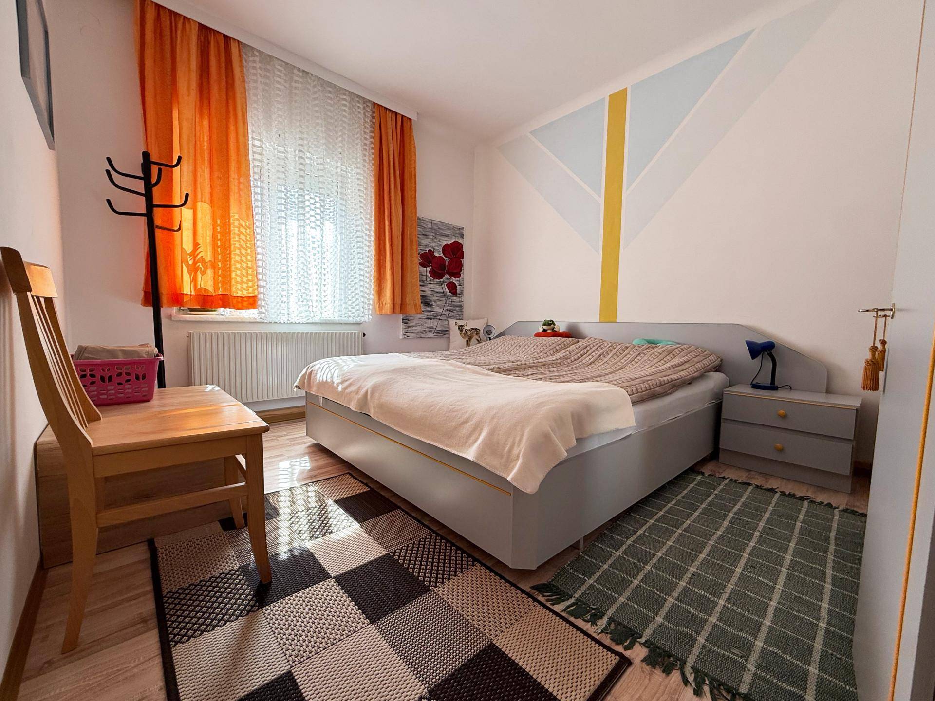 Schlafzimmer mit Doppelbett, farbigen Vorhängen und einer modernen Wandgestaltung.