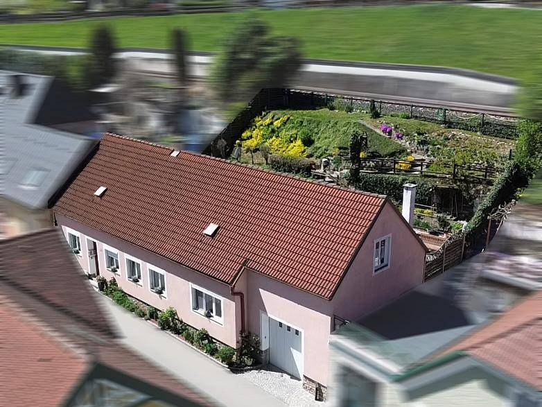Luftaufnahme des Hauses mit rotem Ziegeldach, Garage und einem weitläufigen Gartenbereich.
