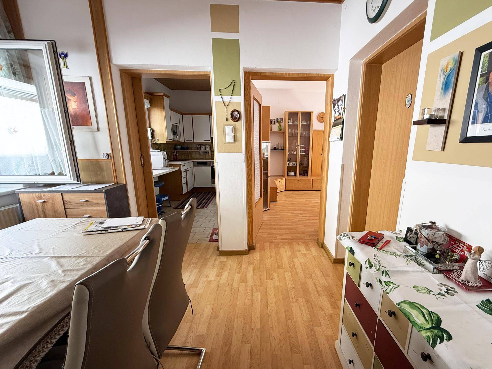 Essbereich mit Holzboden, Esstisch und Blick in die Küche und den Wohnbereich.