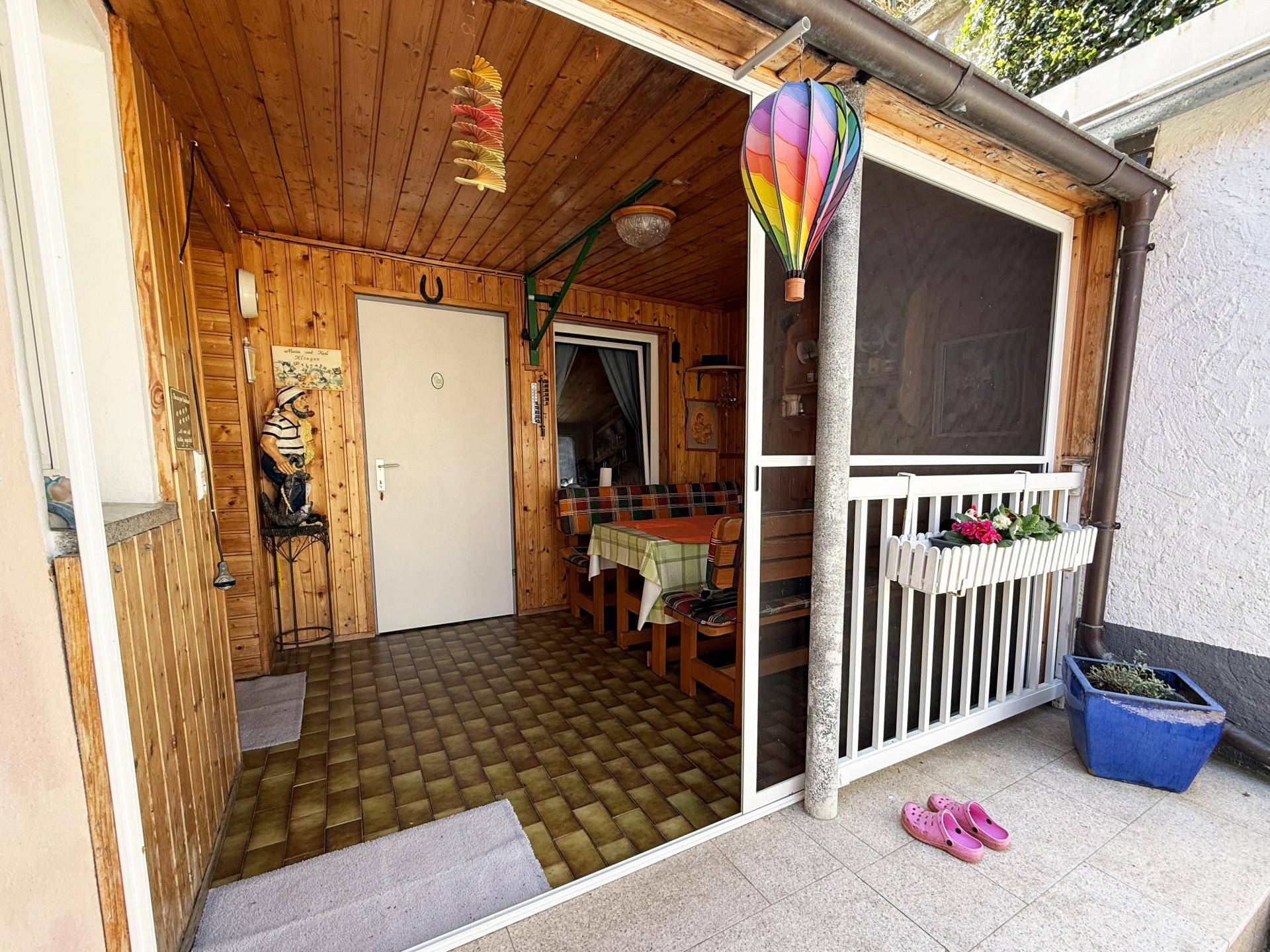 Heller Wintergarten mit Holzverkleidung, Sitzgelegenheiten und Zugang zum Außenbereich.