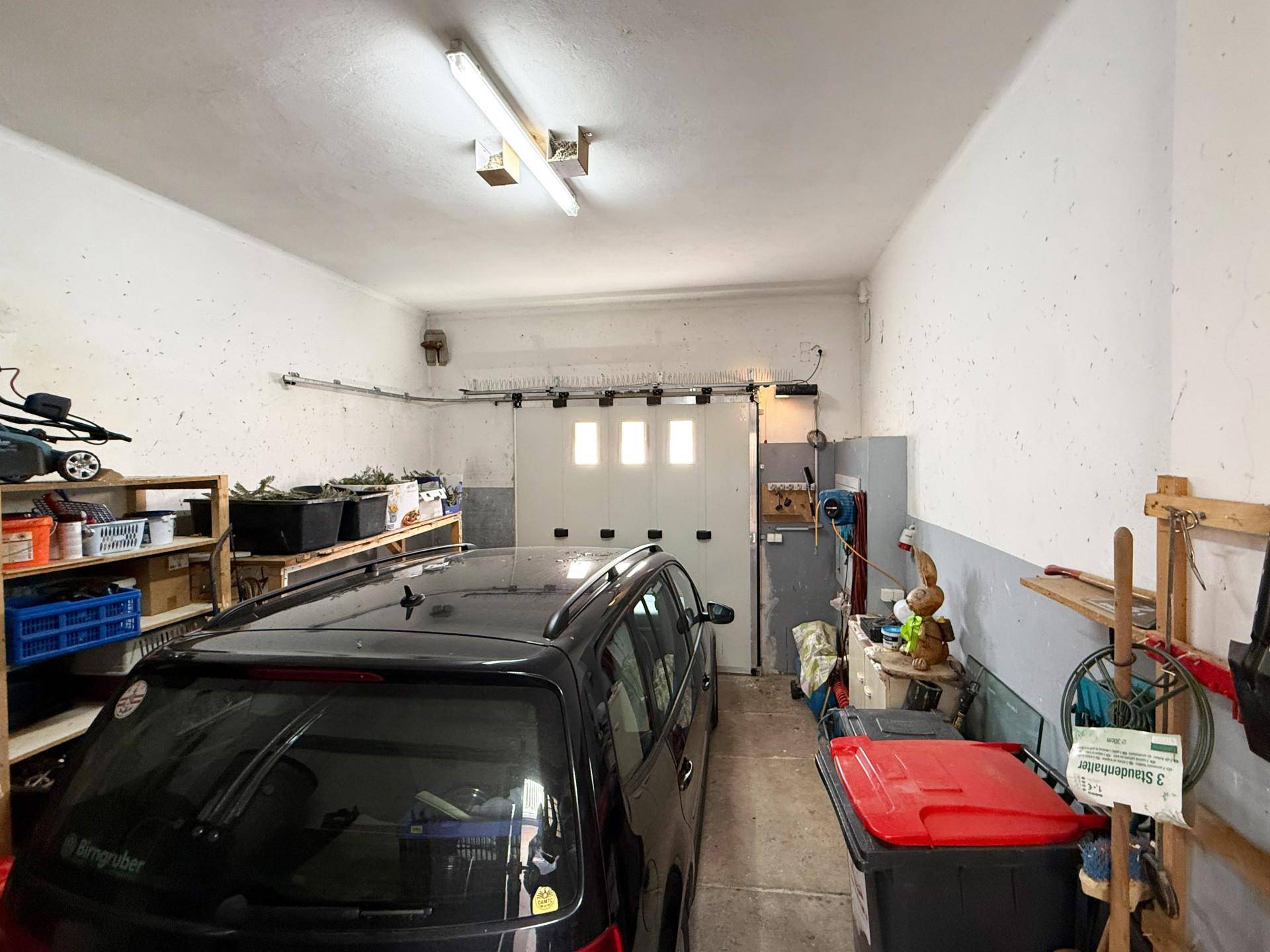 Geräumige Garage mit einem geparkten Auto und Regalen für Lagerung.