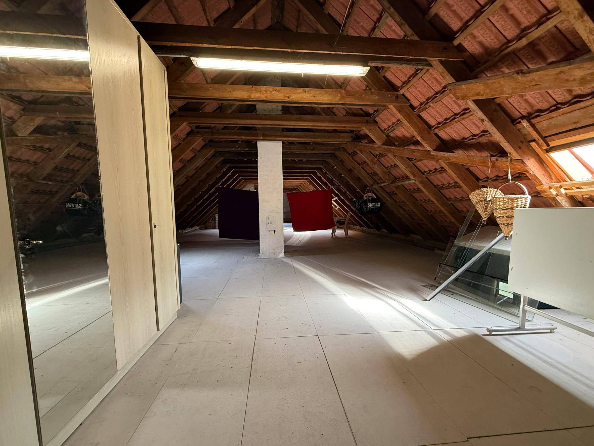 Großer Dachboden mit sichtbaren Holzbalken und Dachfenstern, bereit zum Ausbau.