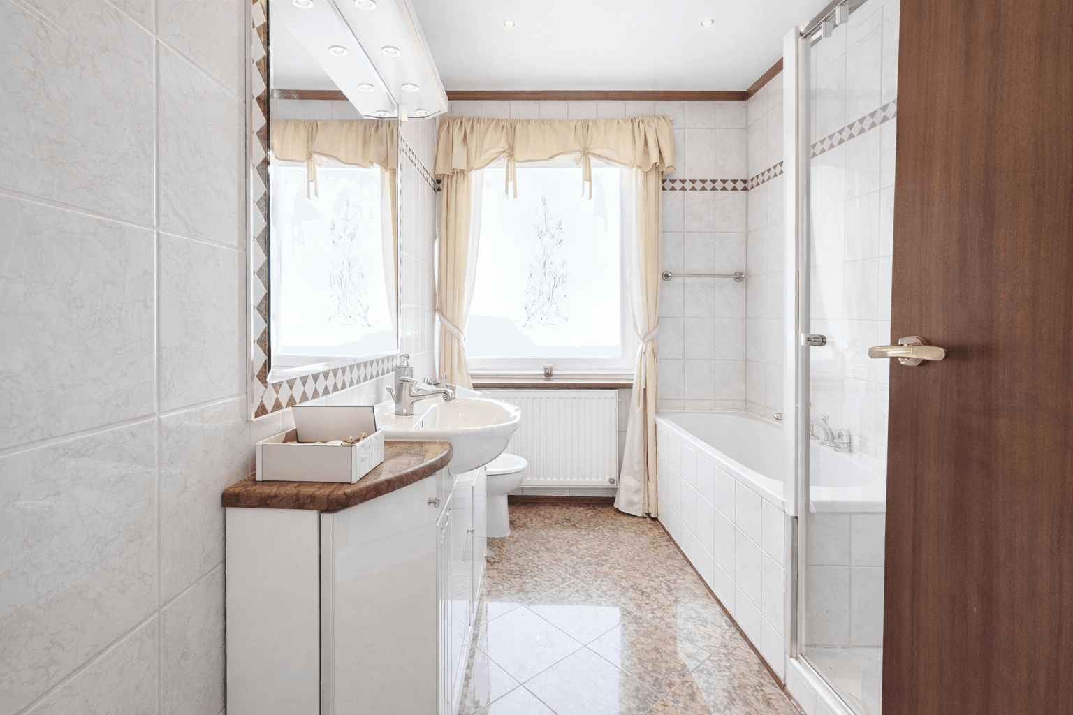 Helles Badezimmer mit Badewanne, Dusche, Einzelwaschbecken und Fenster.