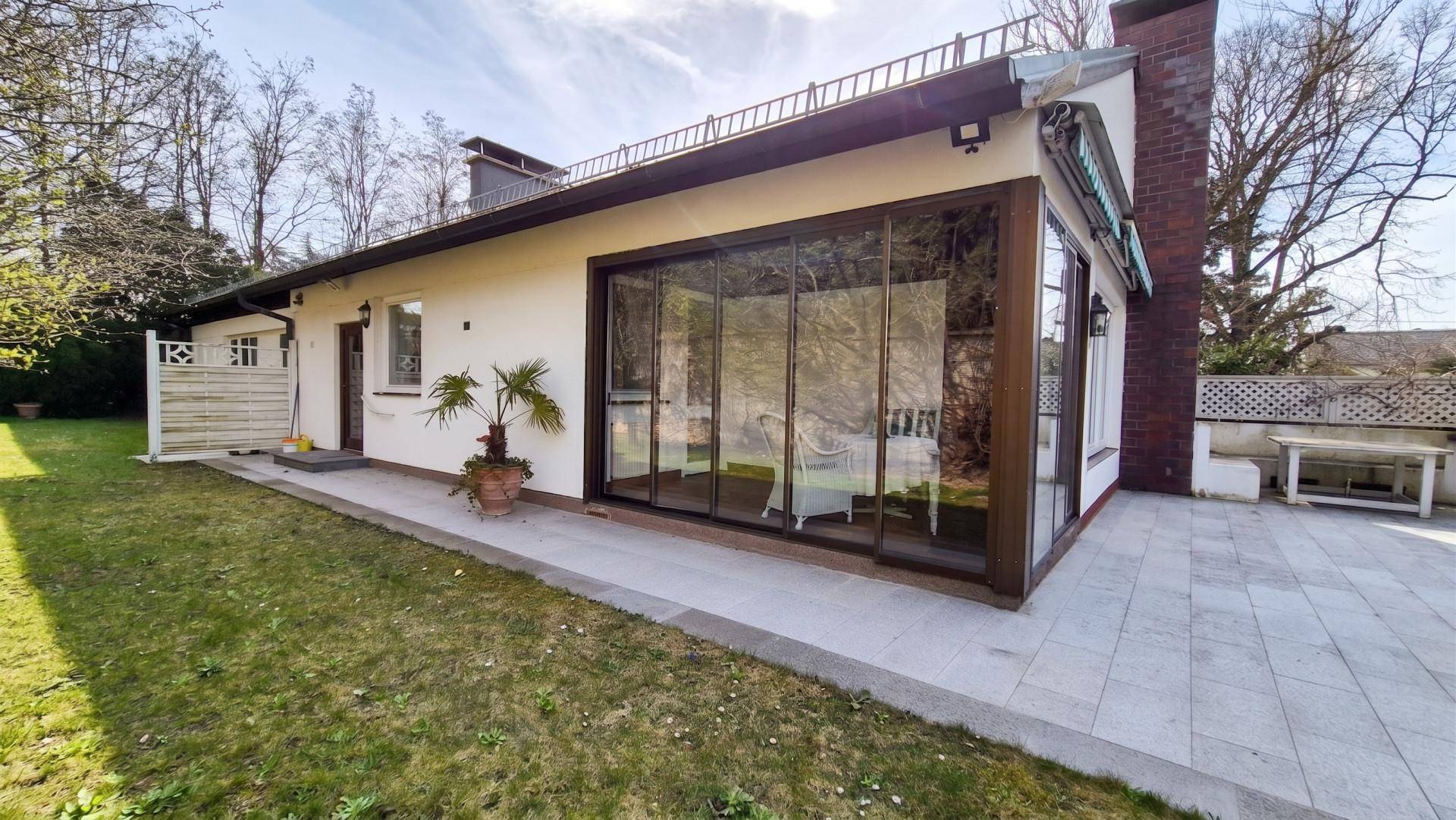 Seitenansicht des Hauses mit Wintergarten, Terrasse und Zugang zum Garten.
