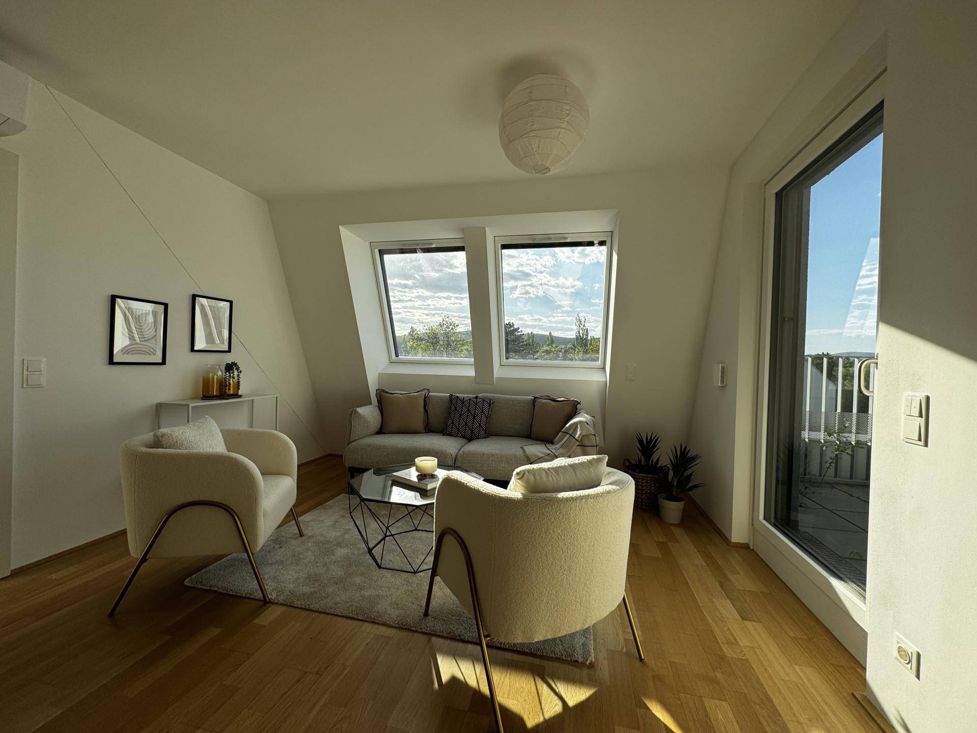 Helles Wohnzimmer mit Holzboden, gemütlichen Sitzgelegenheiten und Dachfenstern mit Ausblick.