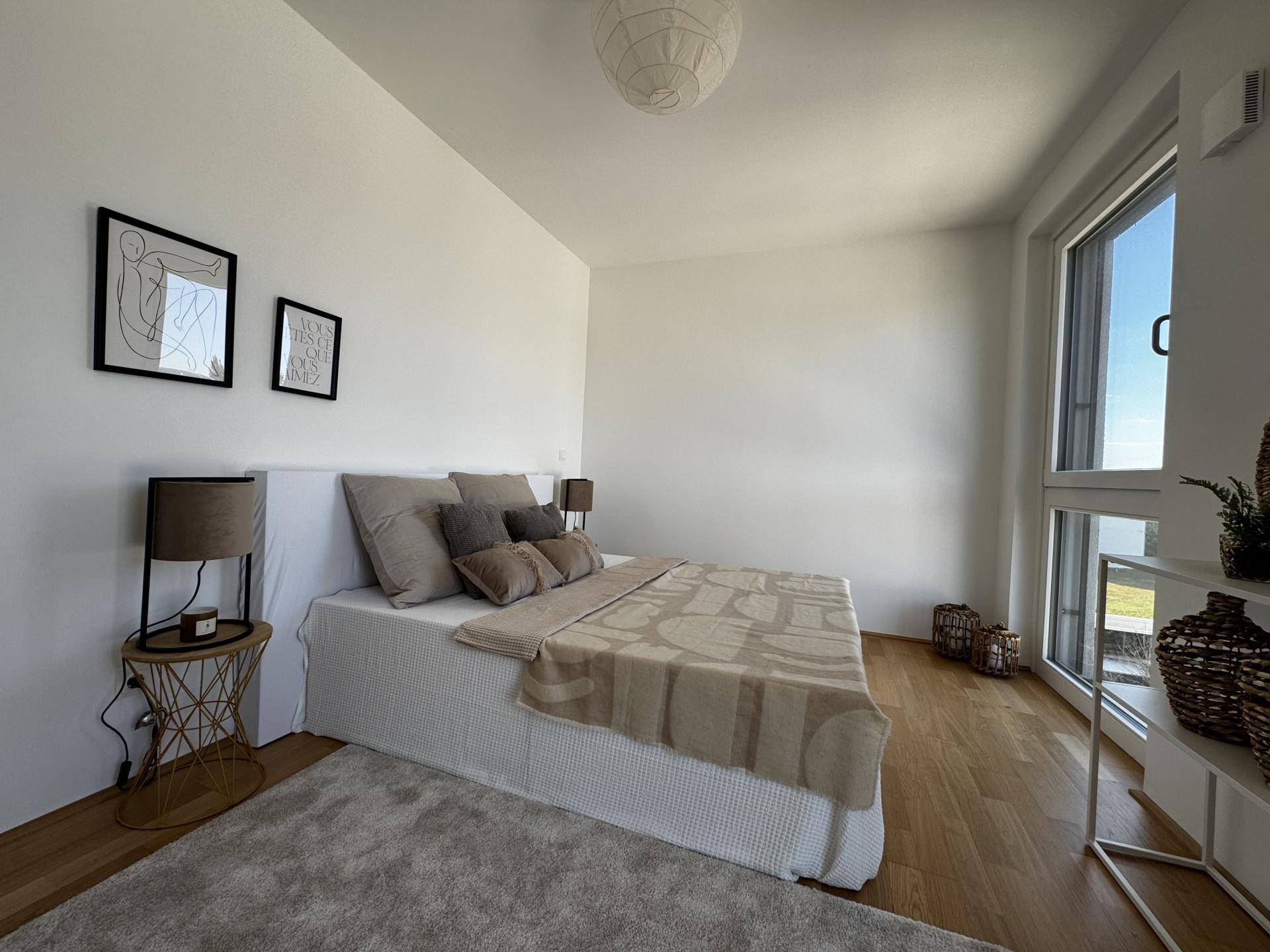 Helles Schlafzimmer mit Holzboden, minimalistischer Einrichtung und viel Tageslicht.