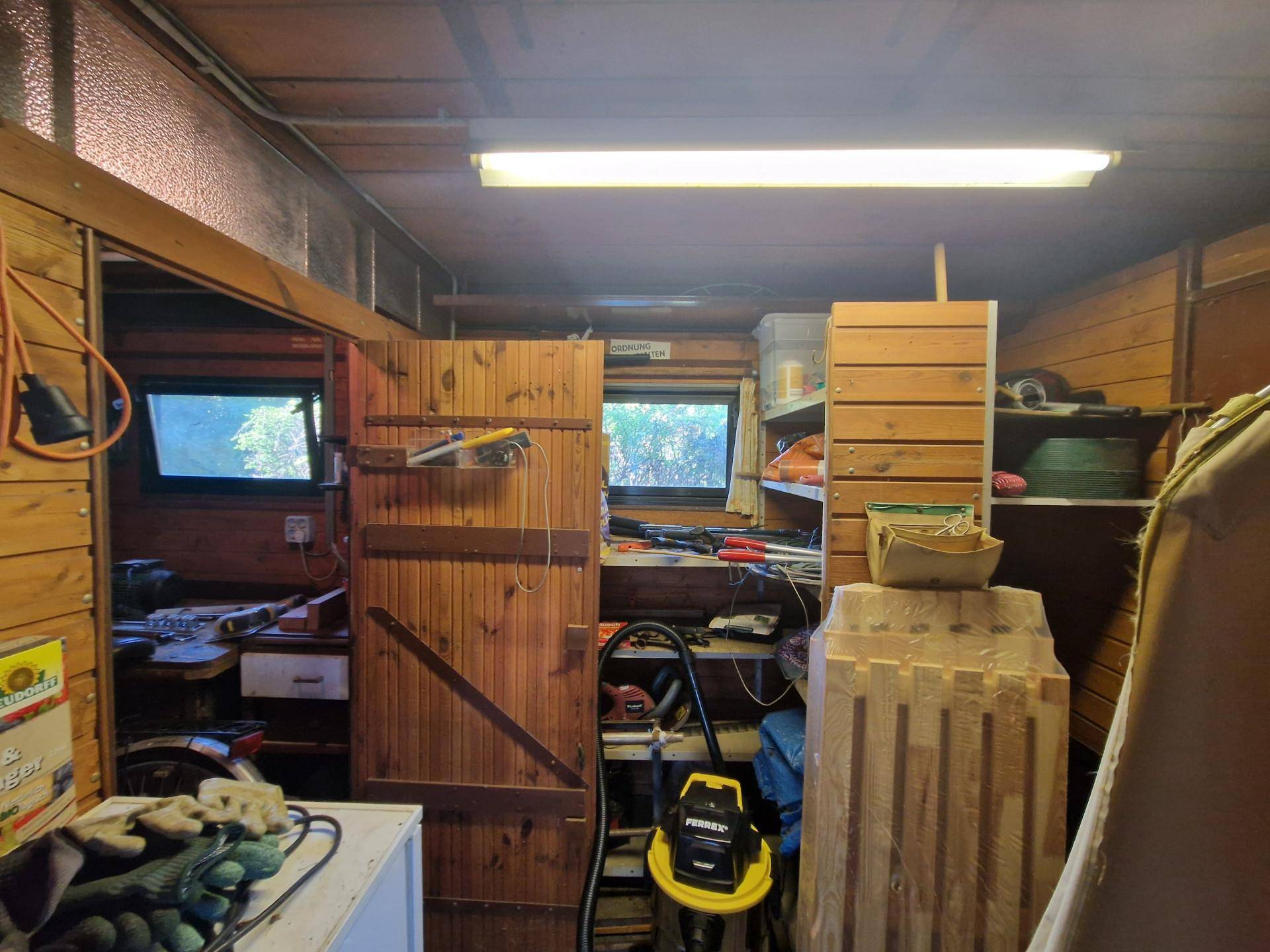 Werkstattraum mit Holzvertäfelung, Regalen und verschiedenen Werkzeugen und Geräten.