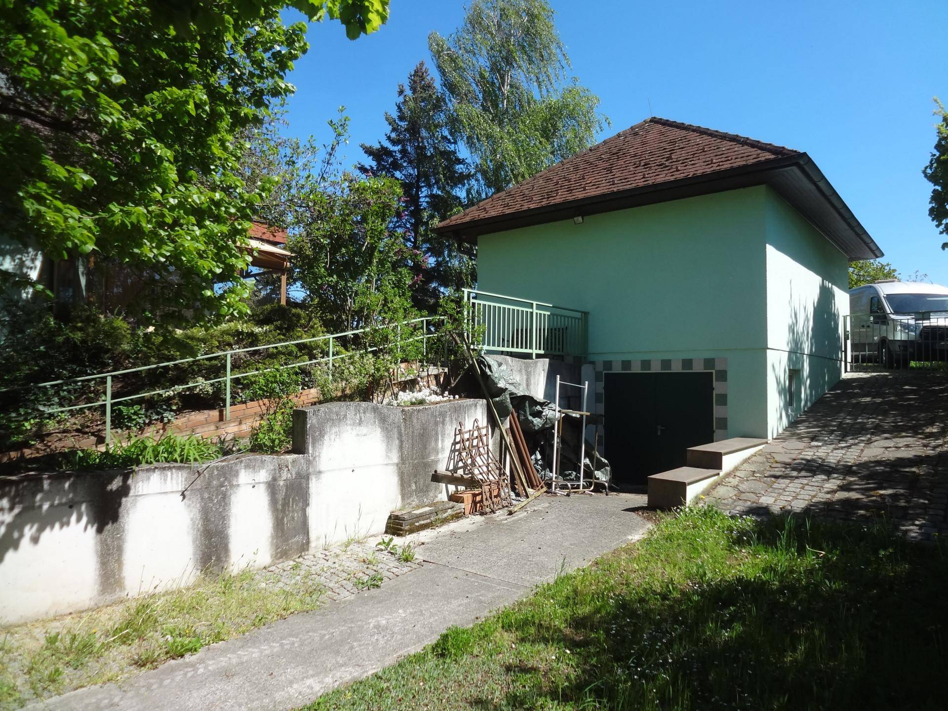 Seitenansicht eines Nebengebäudes mit Garagenzufahrt und einem Treppenaufgang im Freien.