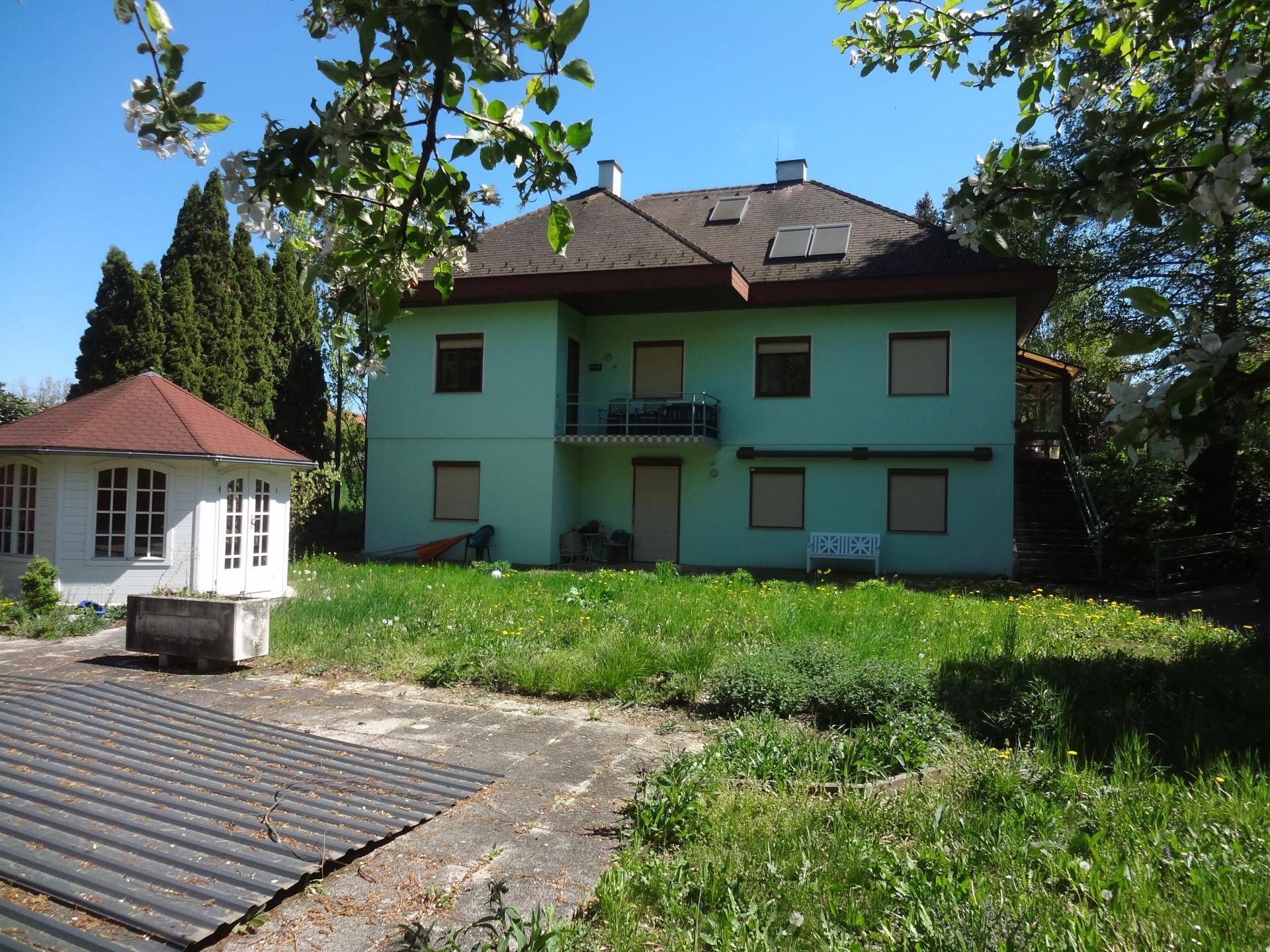 Rückansicht des Hauses mit einem kleinen Balkon, Rasenfläche und einem Gartenpavillon.