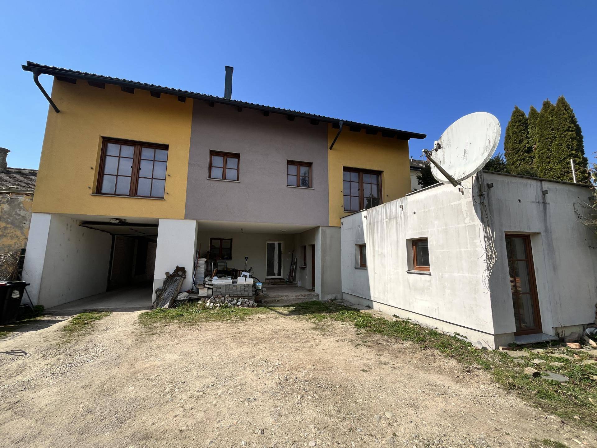 Rückansicht eines Reihenhauses mit gelber und grauer Fassade und Anbau.