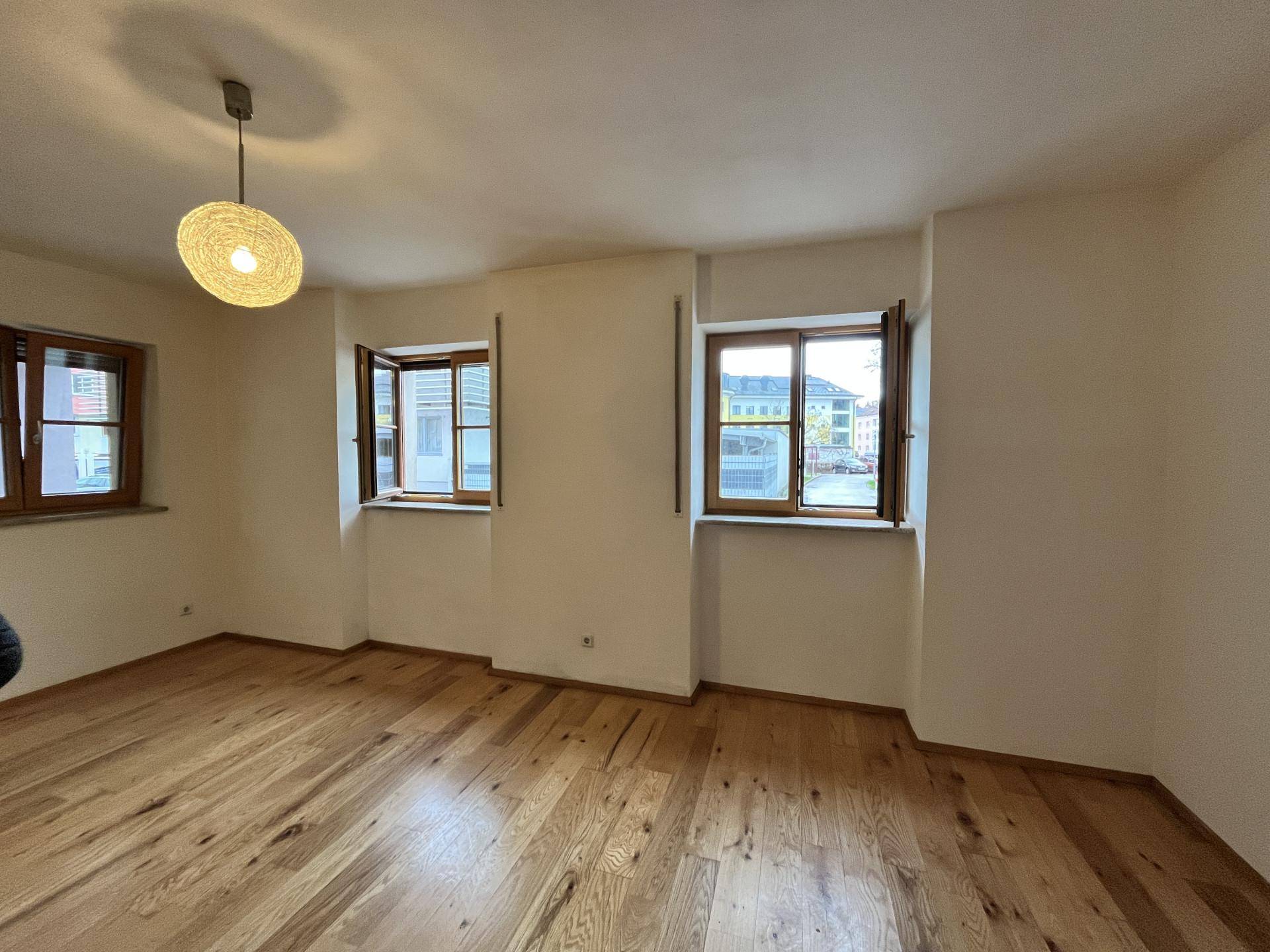 Leerer Raum mit Holzfußboden und mehreren Fenstern, bereit zur individuellen Gestaltung.