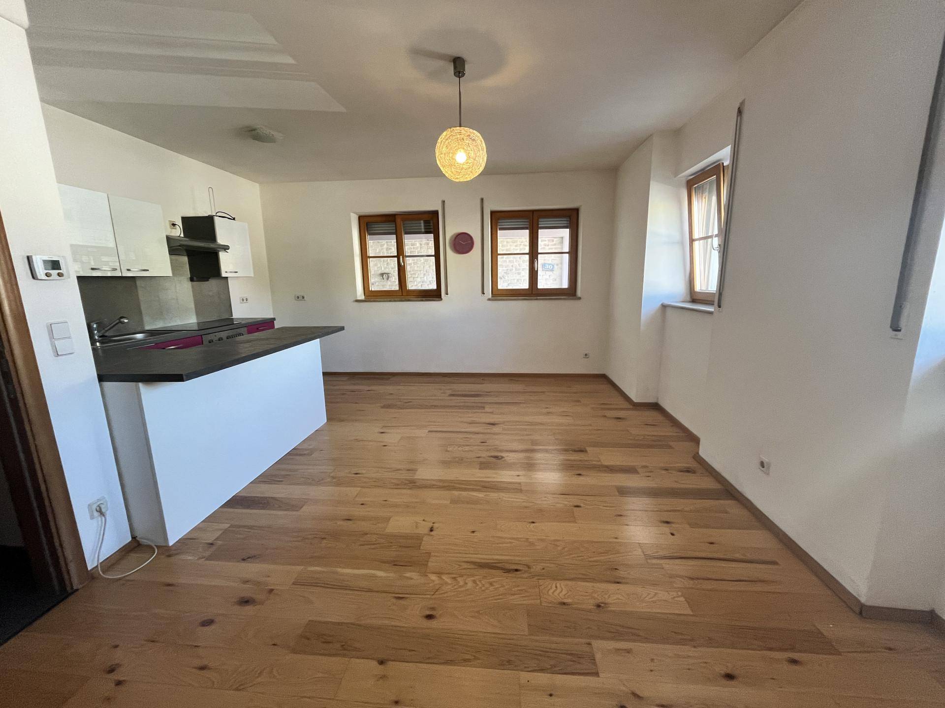 Offene Küche mit Holzfußboden, weißer Küchenzeile und Essbereich.