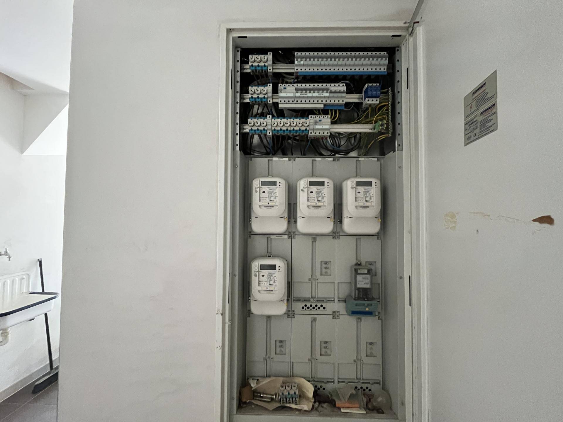 Elektrischer Verteilerkasten mit mehreren Zählern in einem funktionalen Raum.