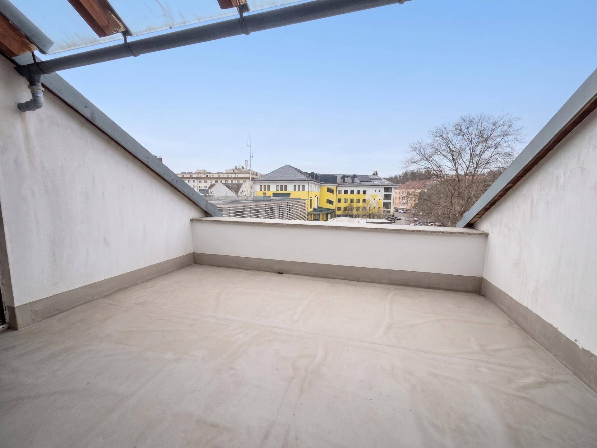 Dachterrasse mit Stadtblick und niedriger Brüstung, ideal zum Entspannen.