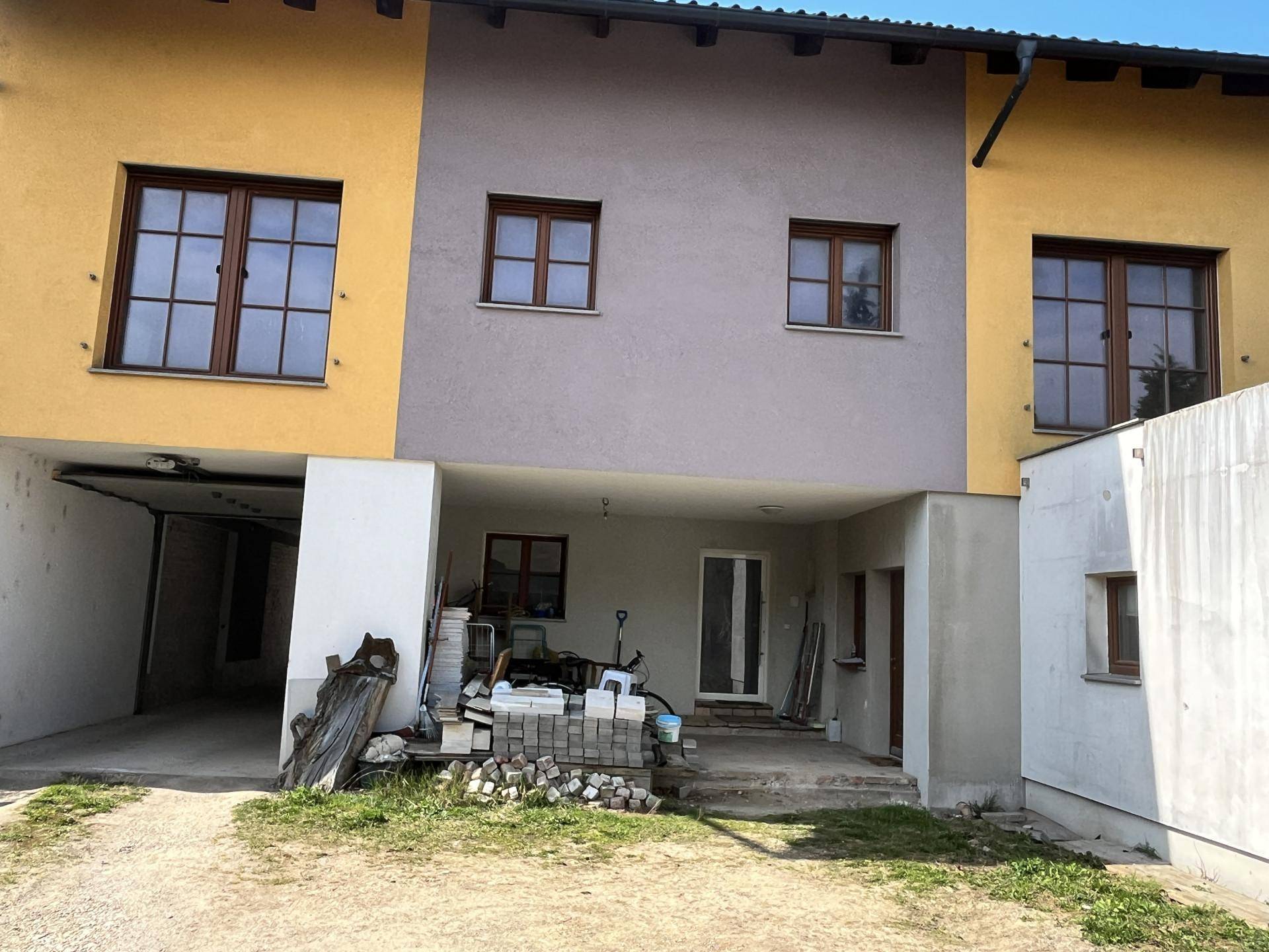 Rückansicht eines Reihenhauses mit gelber und grauer Fassade und Anbau.