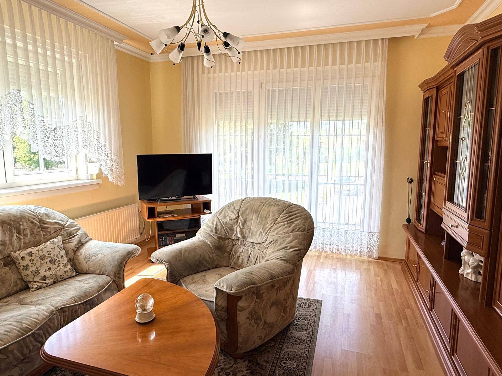 Wohnzimmer mit traditionellen Möbeln, Parkettboden und Zugang zum Balkon.