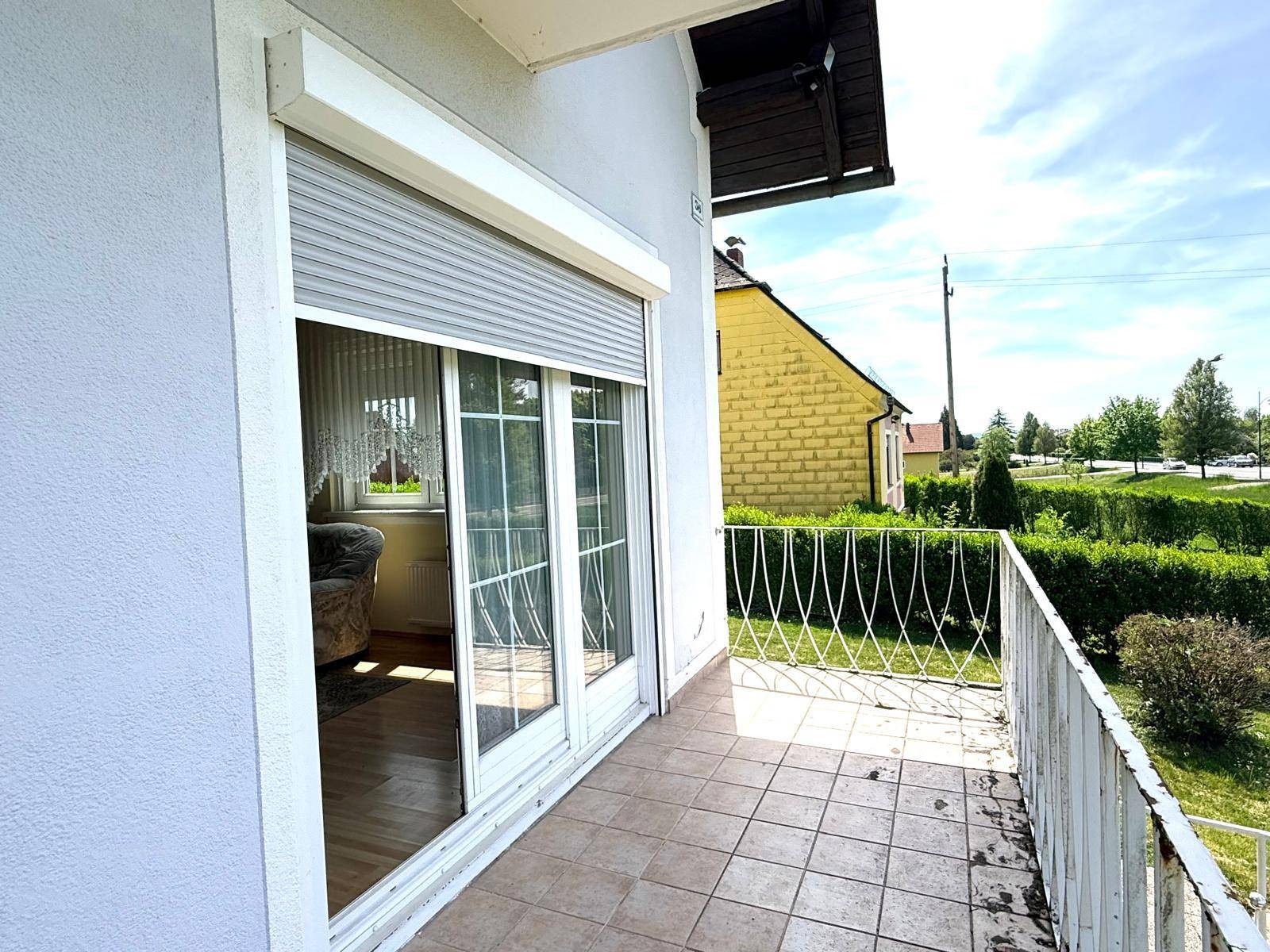 Balkon mit Fliesenboden und Blick auf die grüne Umgebung und Nachbarschaft.