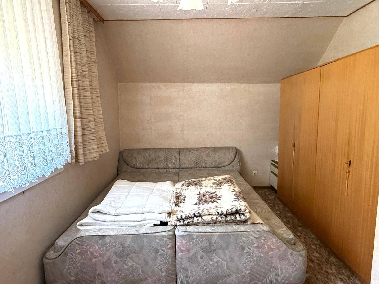 Schlafzimmer im Dachgeschoss mit Doppelbett und Holzschränken.