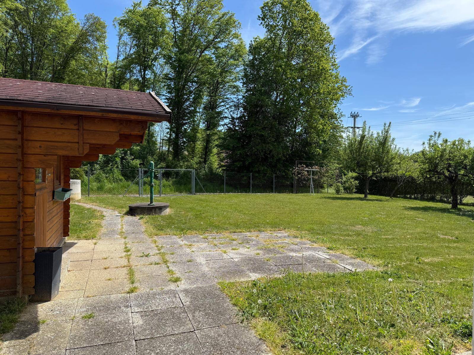 Gartenbereich mit gepflastertem Weg, Rasenfläche und Obstbäumen.