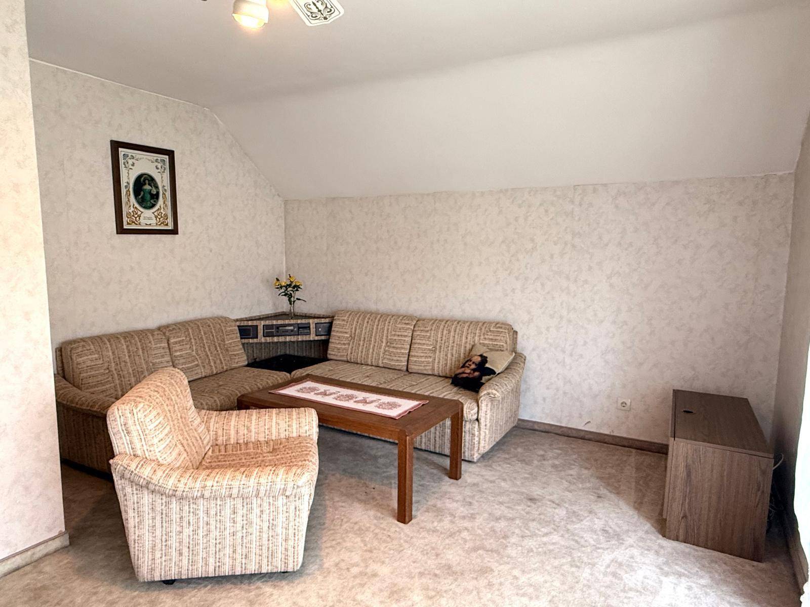 Gemütliches Wohnzimmer im Dachgeschoss mit Ecksofa und Couchtisch.