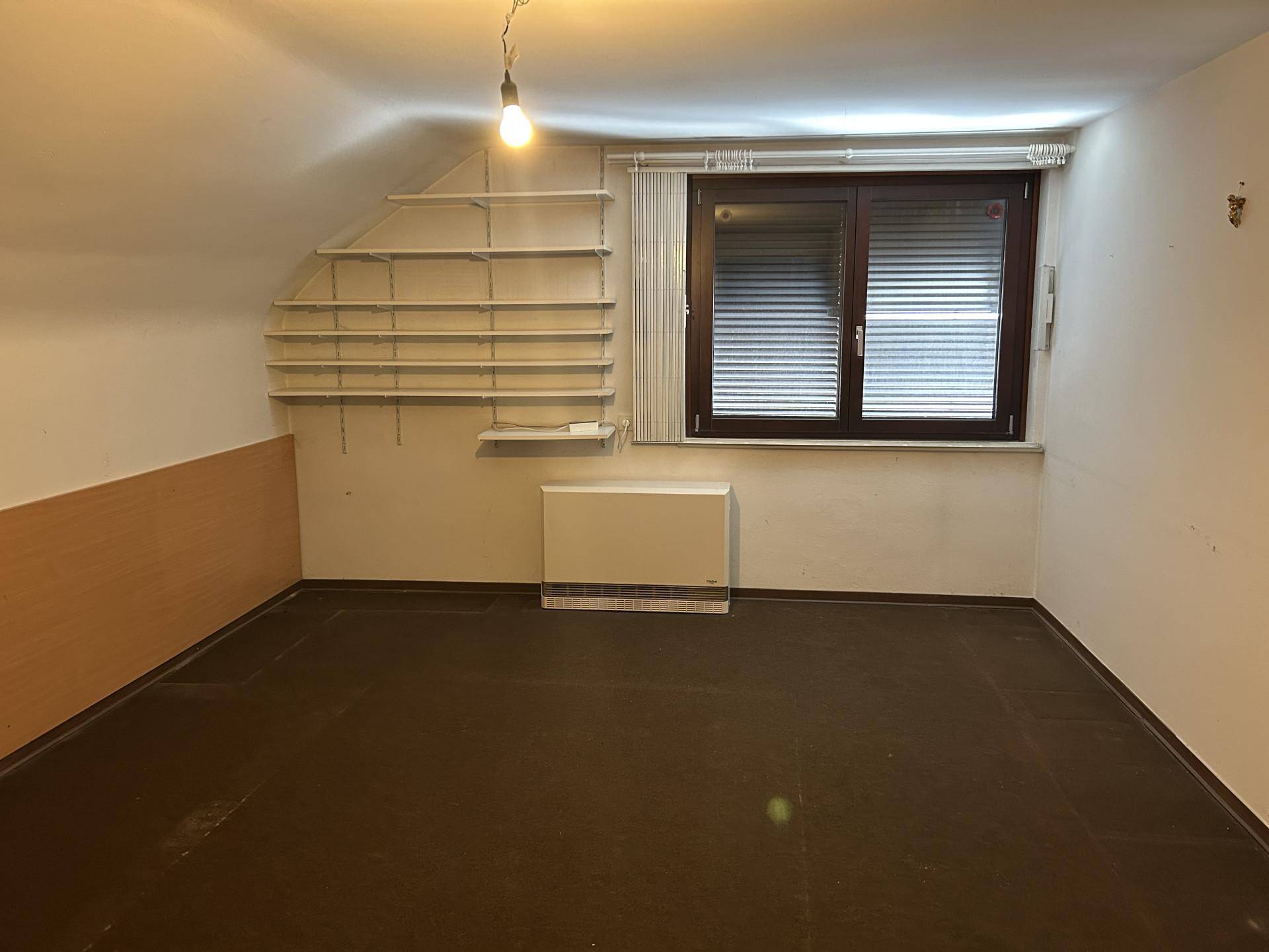 Geräumiges Dachzimmer mit flexiblem Regalsystem und Fenster, ideal für Stauraum oder als Hobbyraum.