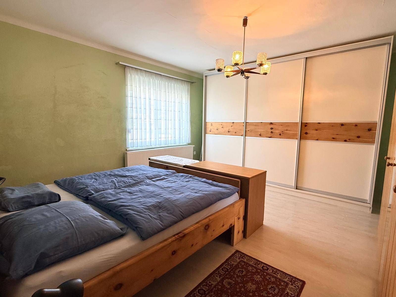 Schlafzimmer mit Doppelbett, großem Einbauschrank und hellem Laminatboden.