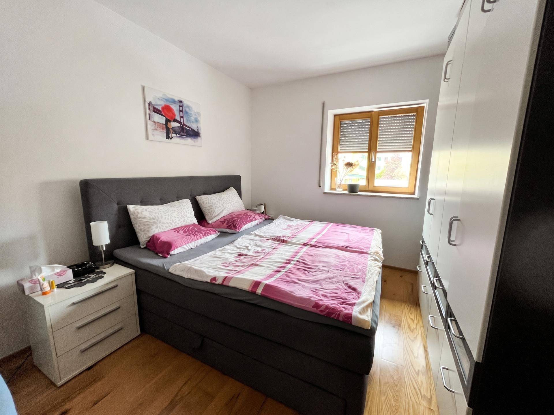 Gemütliches Schlafzimmer mit Doppelbett, Holzfußboden und weißem Kleiderschrank.