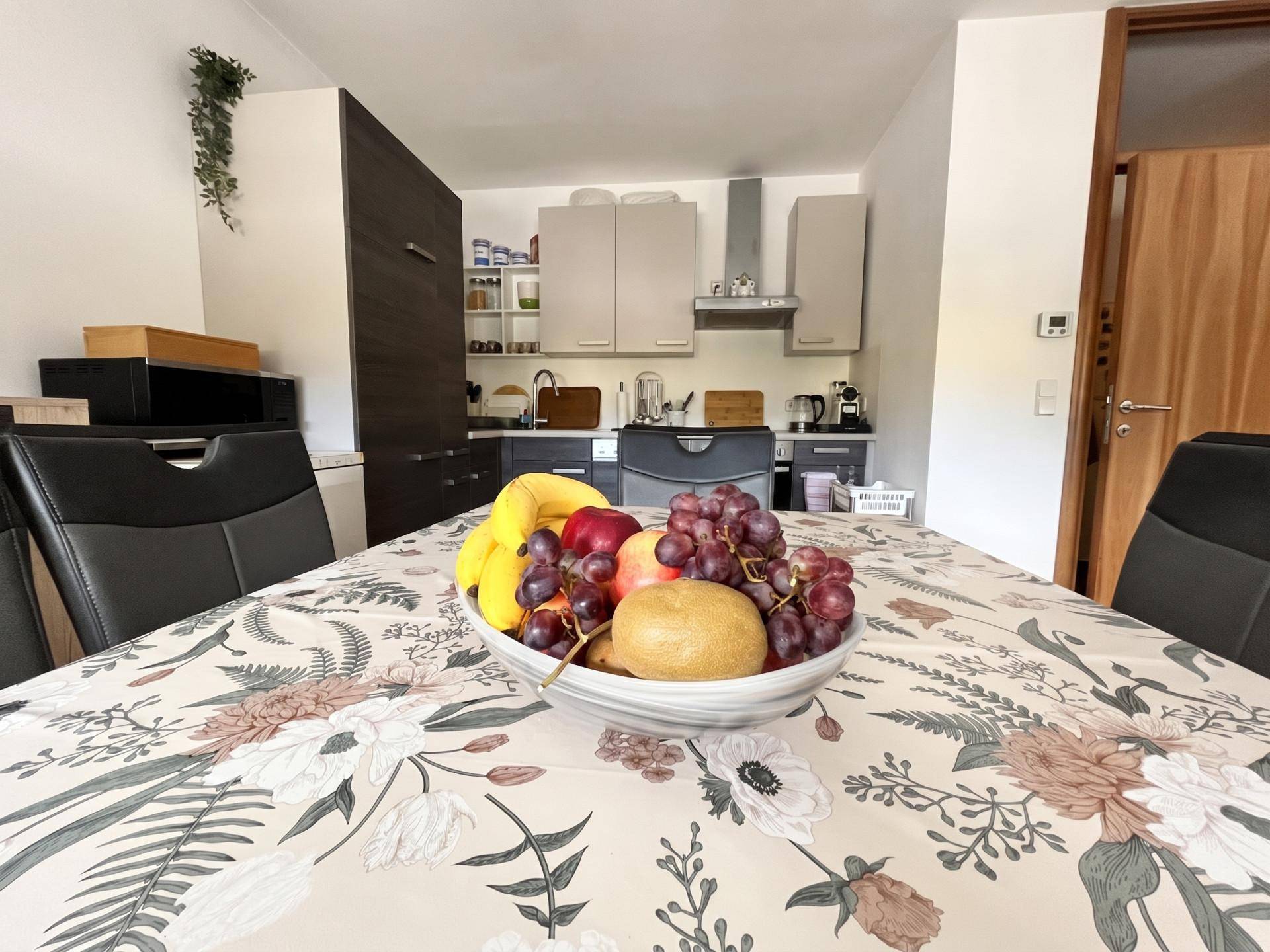 Moderne Küche mit Esstisch, dunklen Schränken und integrierten Geräten.