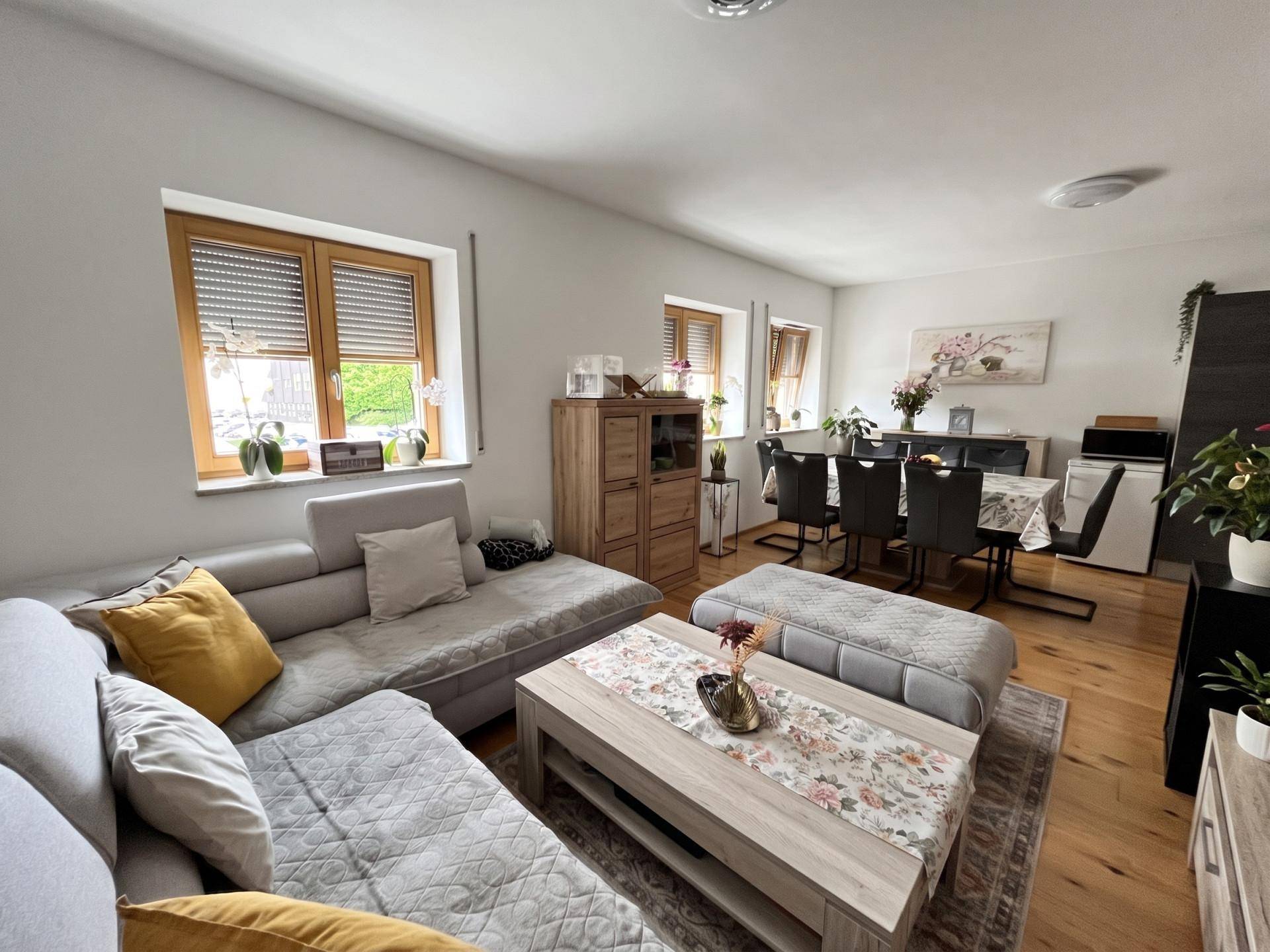 Geräumiger Wohn-Essbereich mit Ecksofa, Esstisch und Holzfußboden.