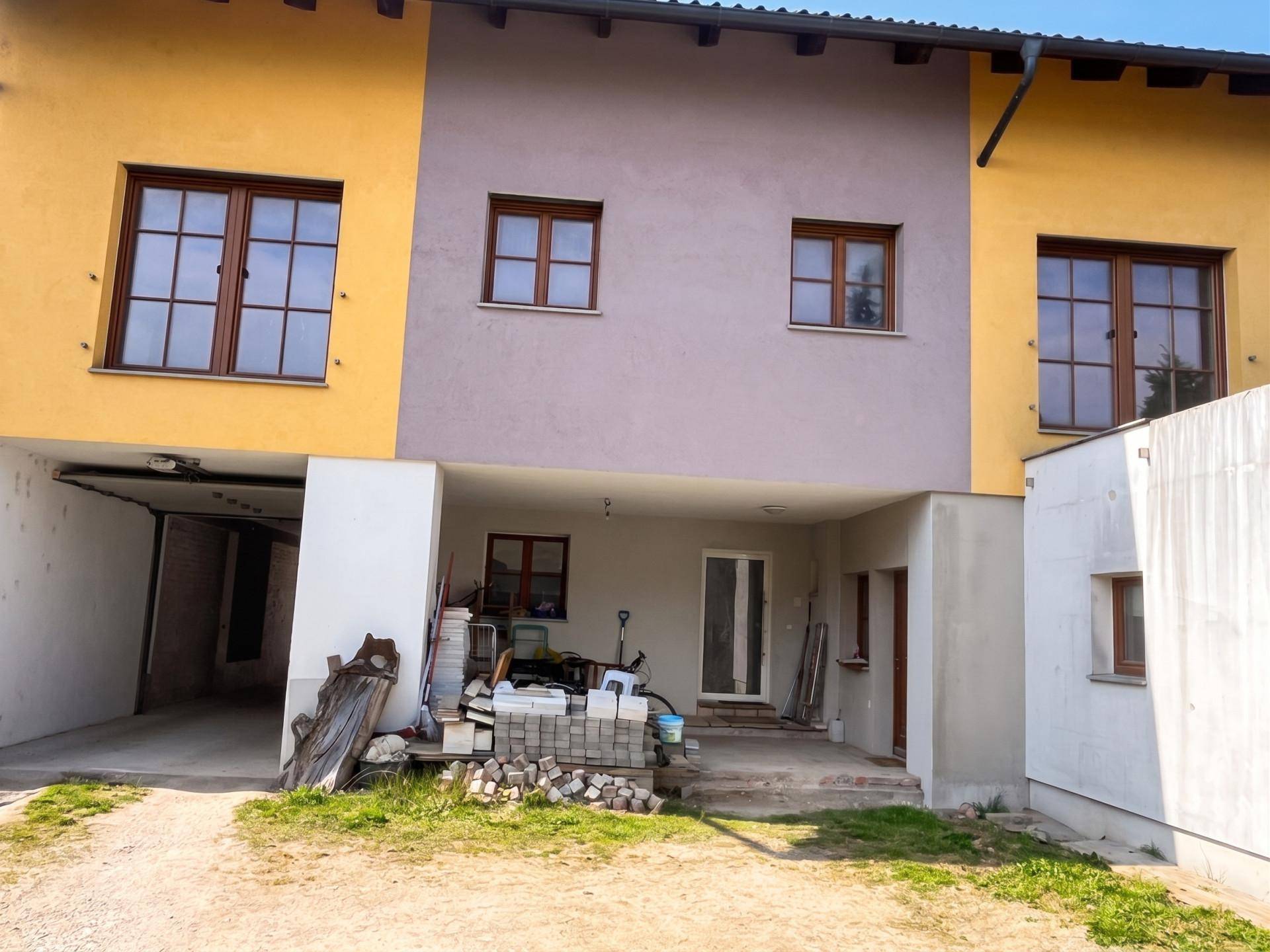 Rückansicht eines Reihenhauses mit gelber und grauer Fassade und Anbau.