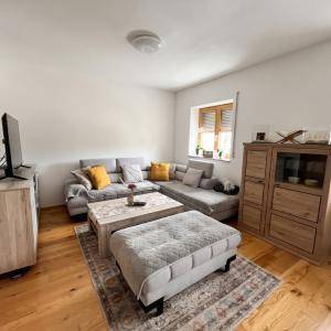 Gemütliches Wohnzimmer mit Ecksofa, Couchtisch und Holzmöbeln, gut beleuchtet durch ein Fenster.