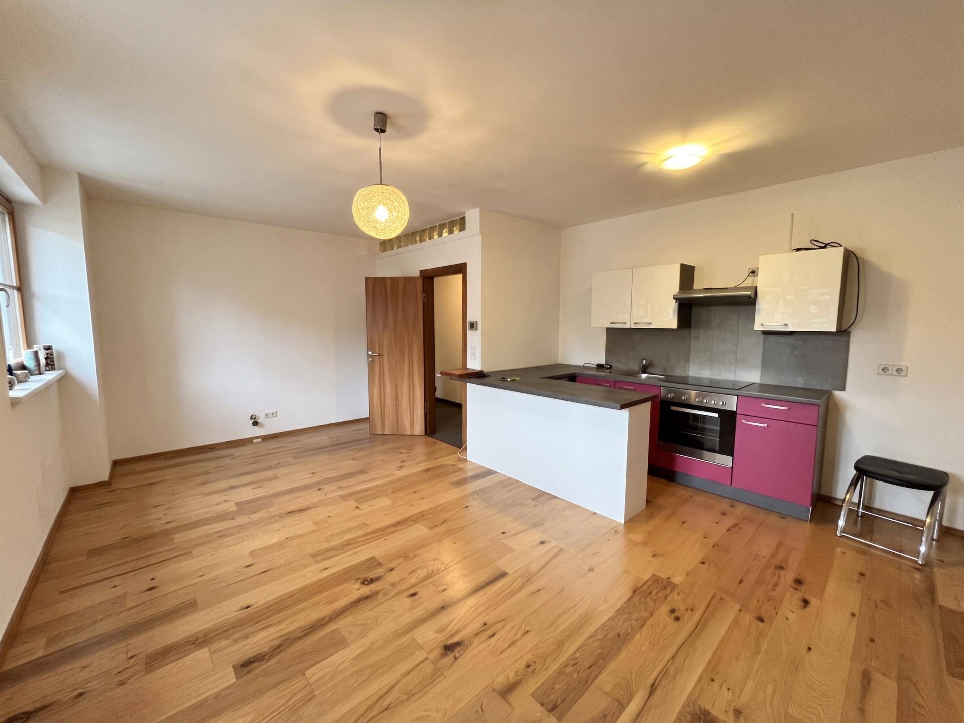 Offene Küche mit Holzfußboden, weißer Küchenzeile und Essbereich.