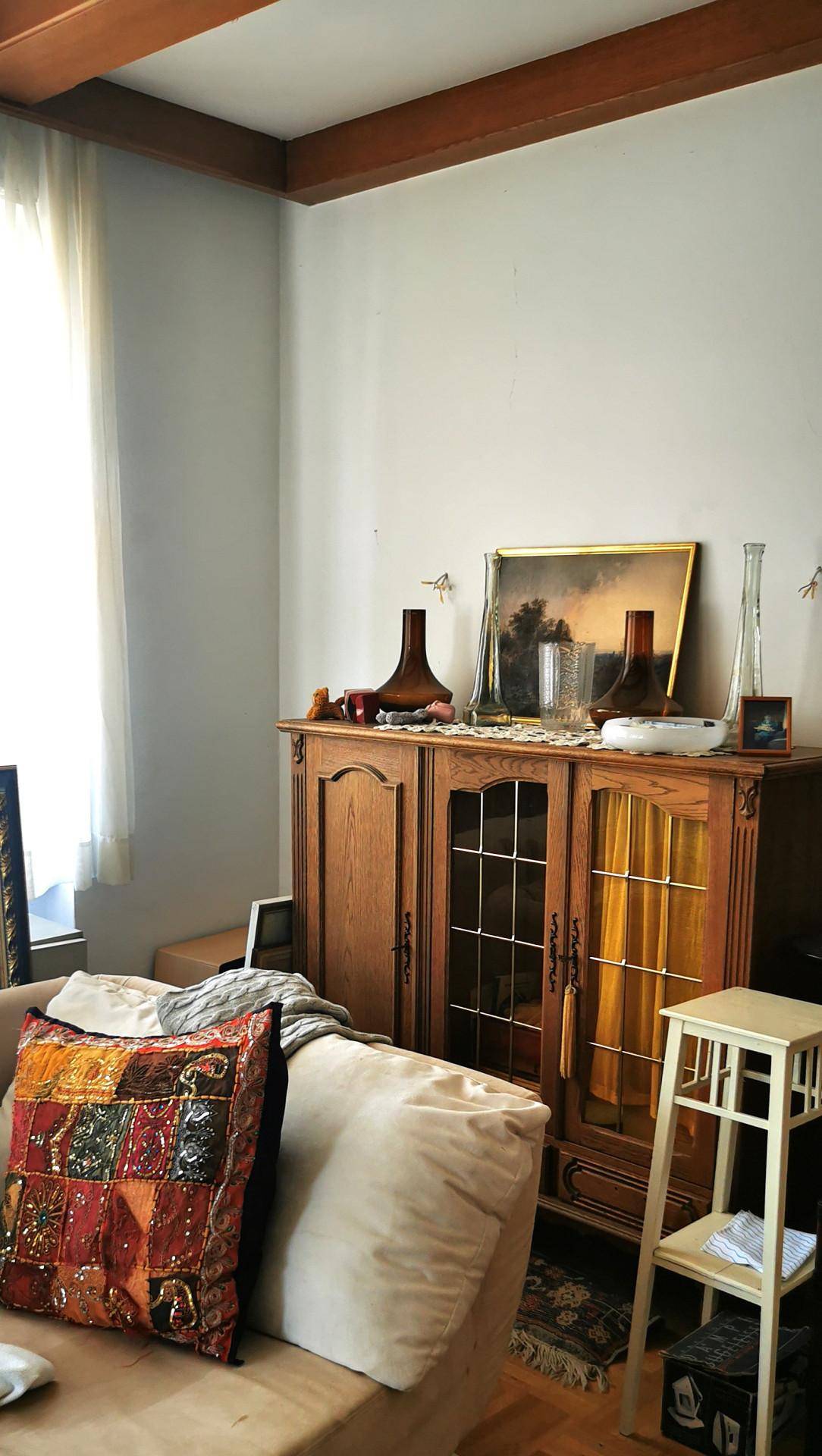 Gemütliche Wohnzimmerecke mit Holzschrank, Sofa und sichtbaren Deckenbalken, traditionell eingerichtet.