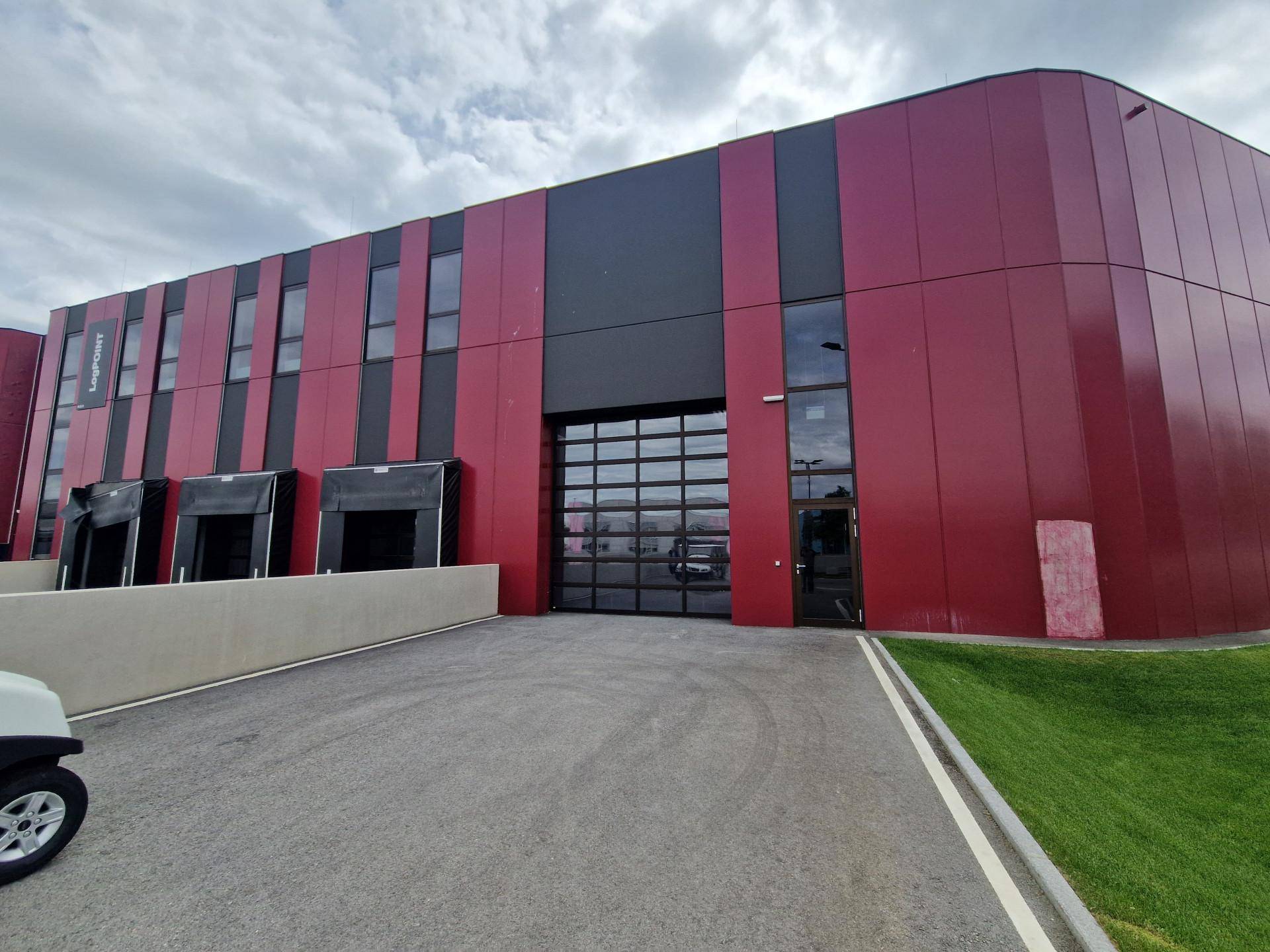 Rotes und schwarzes Industriegebäude mit Laderampen und einem großen Rolltor.