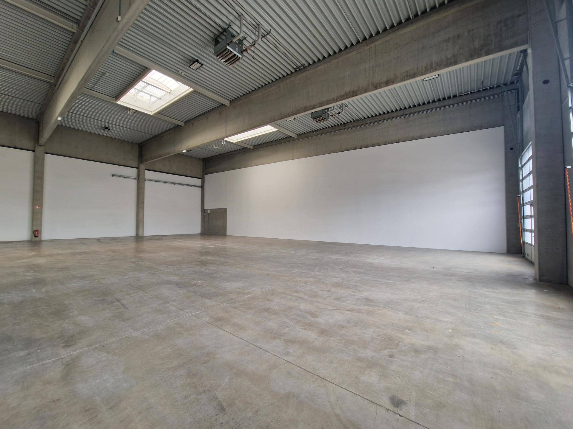 Geräumige Lagerhalle mit Betonboden, hohen Decken und Oberlichtern.