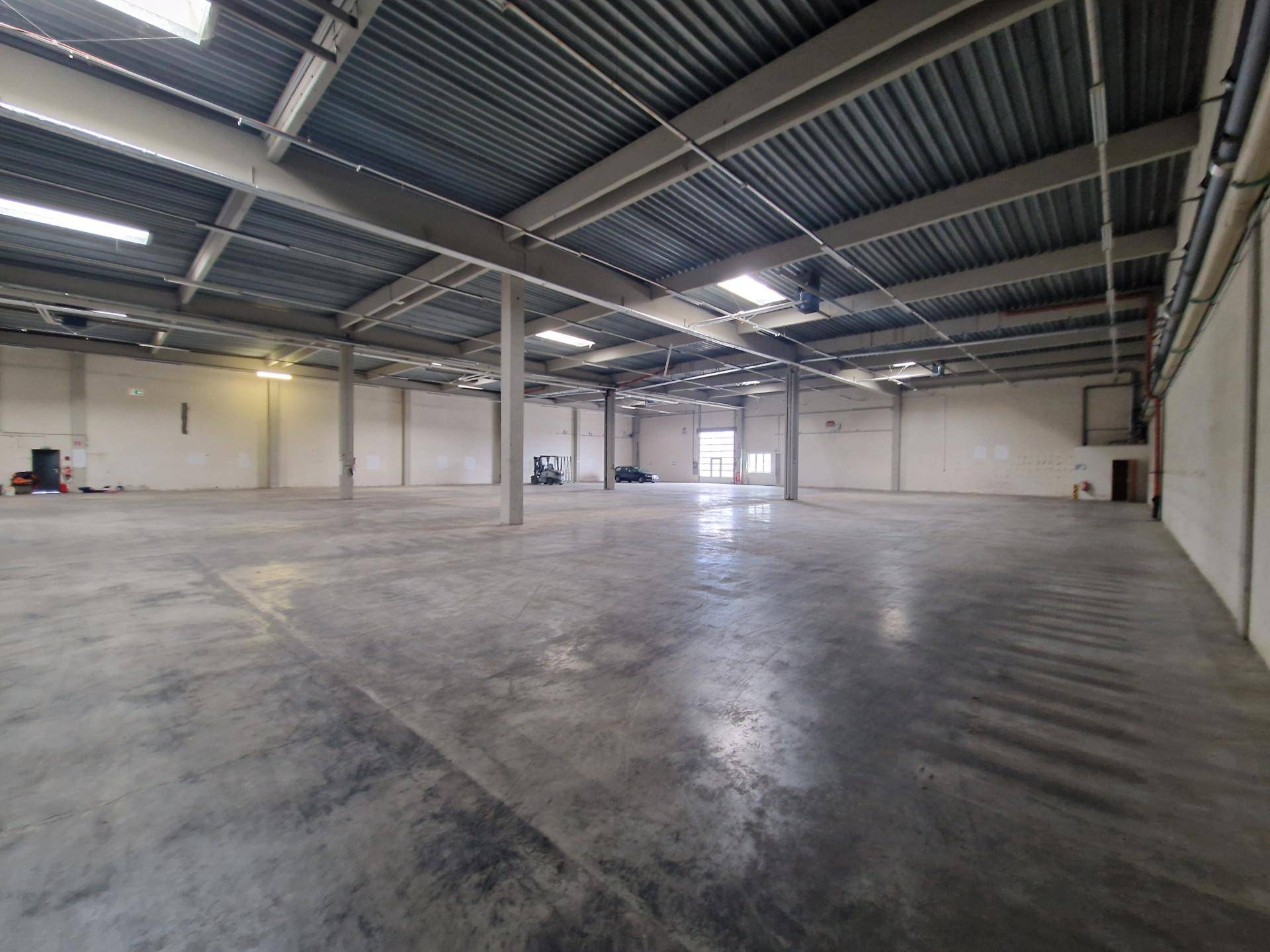 Geräumige Lagerhalle mit Betonboden, hohen Decken und Oberlichtern.