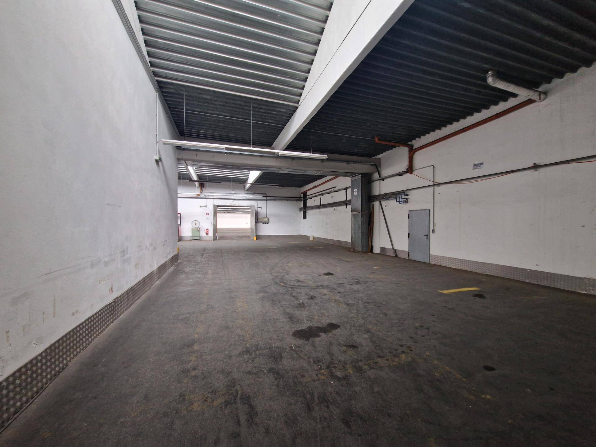 Laderampe oder Eingangsbereich einer Lagerhalle mit dunklem Boden und Rolltor.