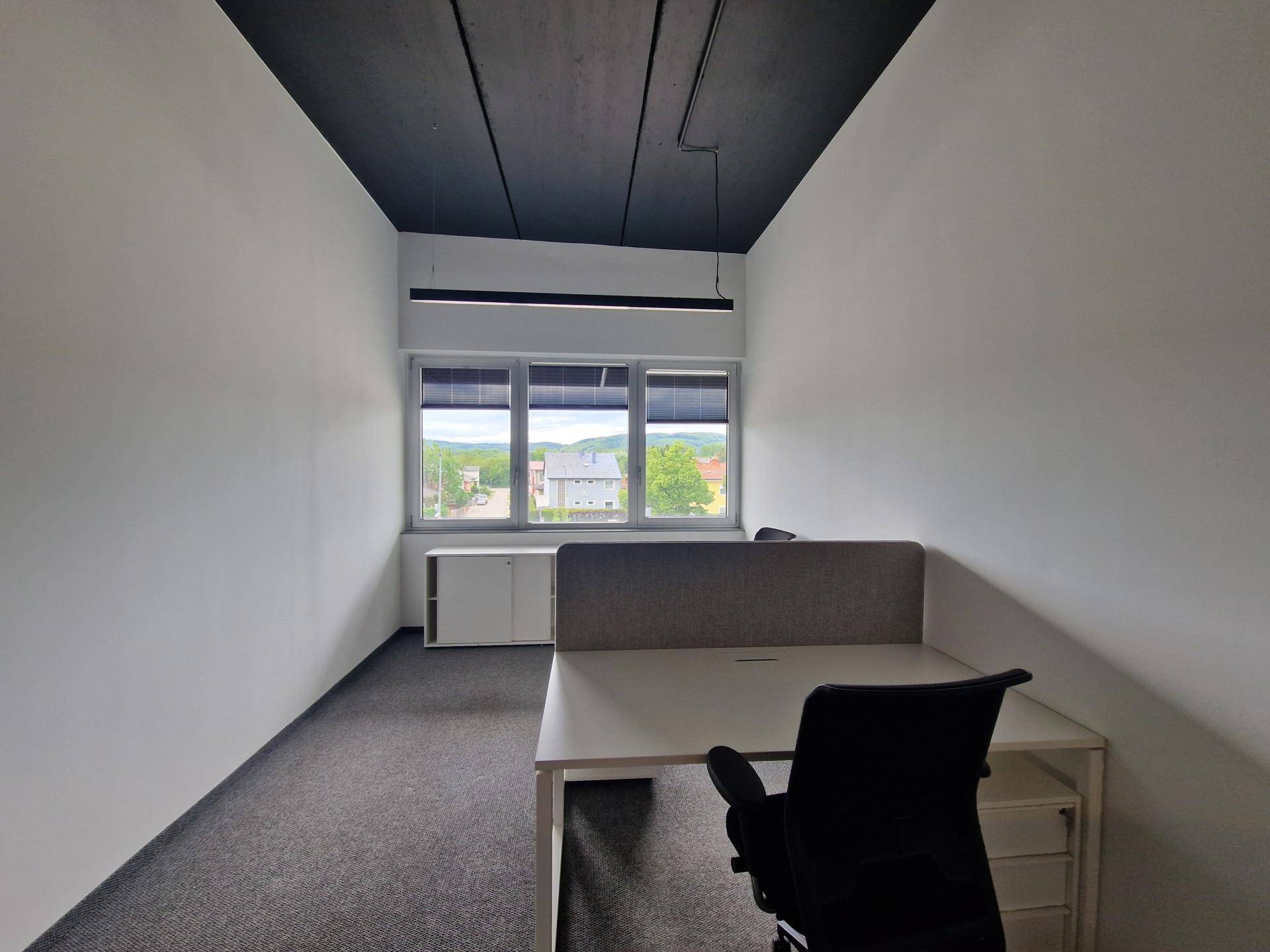 Helles Einzelbüro mit Schreibtisch, Bürostuhl und Blick ins Grüne durch das Fenster.
