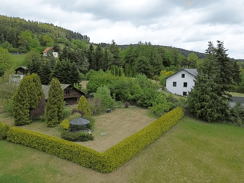Gesamtansicht des Anwesens mit beiden Häusern, gepflegtem Garten, Hecken und einem Pavillon.