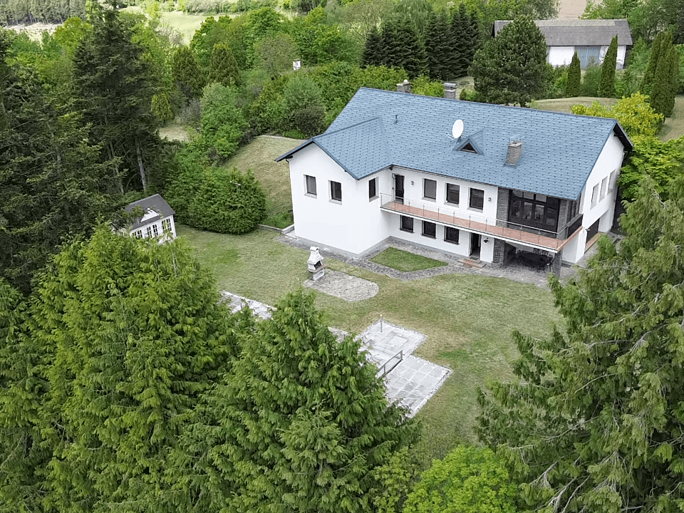 Luftaufnahme des Haupthauses mit großem Garten, Grillplatz und einem kleinen Nebengebäude.